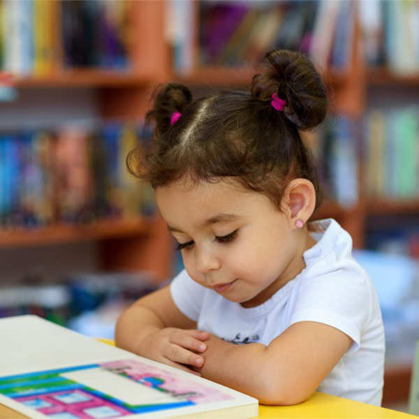 Happy child little girl reading a book.